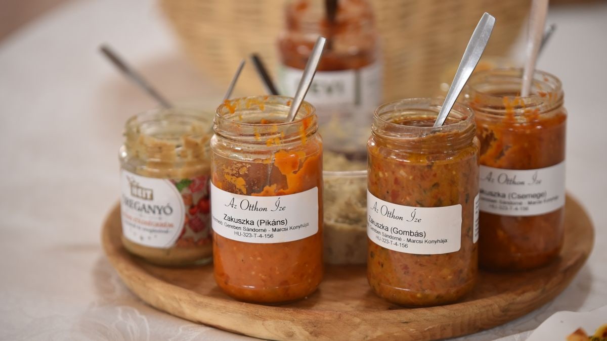 A selection of Hungarian vegetable spreads in jars on a wooden tray.